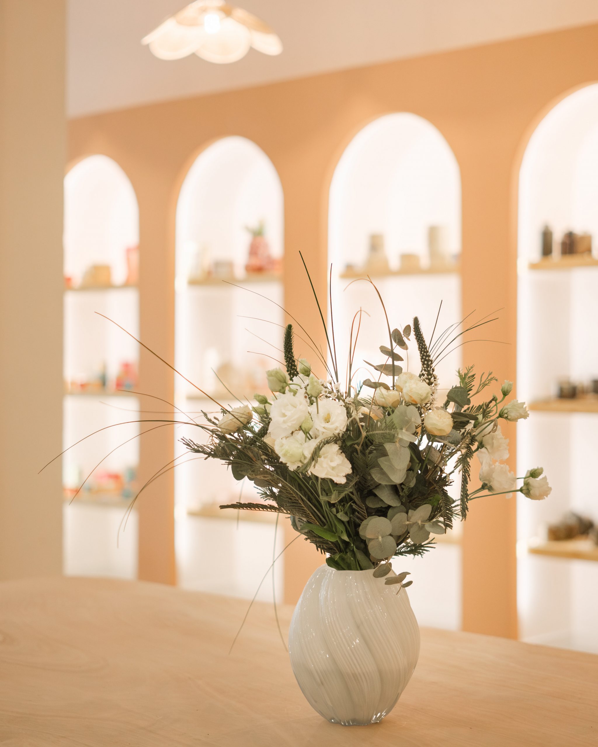 Détail des arches de présentation en teinte rose terracotta, intégrant des niches pour exposer les créations en céramique. Un élément architectural fort qui structure l’espace et participe à l’identité du lieu, conçu par KLZ Studio à Antibes.